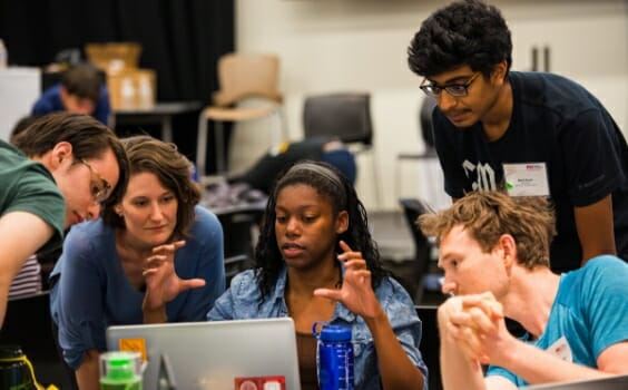 A group of students collaborate around a computer at an ASU-sponsored event