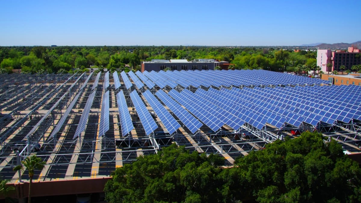 Aerial photo of a field of solar panels surrounded by greenery.