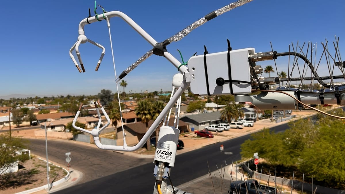 White instrument with lots of sensor wires hangs above a Phoenix neighborhood street corner.