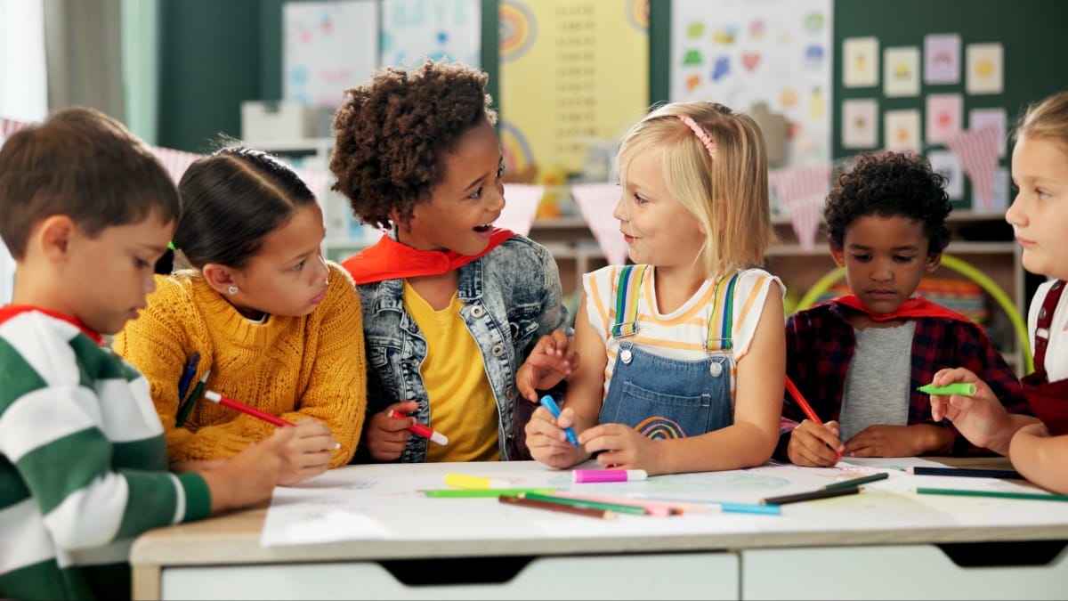 Children talk to each other while working together at a schoolroom desk